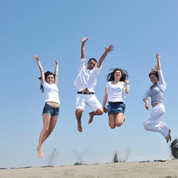Gruppe junger Menschen springt vor Freude am Strand, symbolisiert Vorteile der Arbeit als sektoraler Heilpraktiker in der Physiotherapie