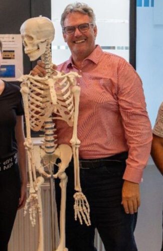 Lehrer:in und Skelettmodell gemeinsam im Biologieunterricht